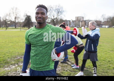 Portrait confident young man boxing in park with friends Stock Photo