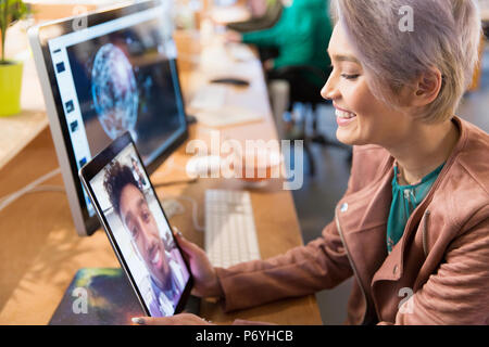 Creative businesswoman video chatting with colleague on digital tablet in office Stock Photo