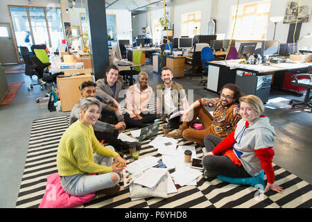 Portrait confident creative business team meeting, brainstorming in circle on office floor Stock Photo