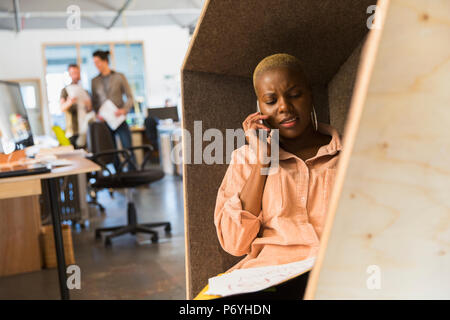 Creative businesswoman talking on smart phone in office cubby Stock Photo