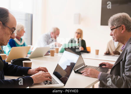Senior businessmen using laptops in conference room meeting Stock Photo