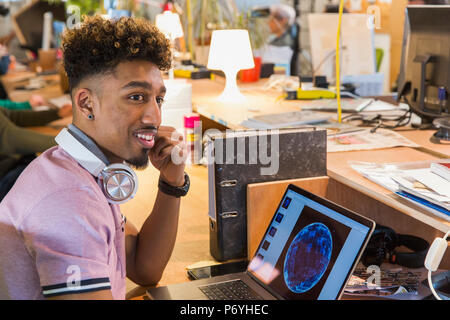 Creative businessman with headphones working at laptop in office Stock Photo
