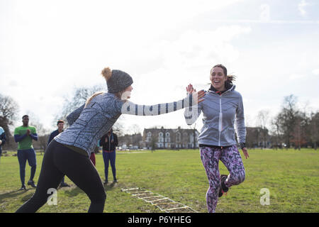 Women high-fiving, exercising in park Stock Photo