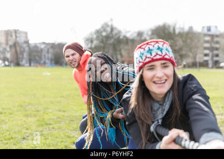 Determined team pulling rope in tug-of-war in park Stock Photo