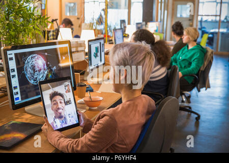 Creative businesswoman video chatting with businessman on digital tablet in open plan office Stock Photo