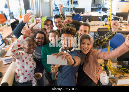 Enthusiastic creative business team cheering, taking selfie in office Stock Photo