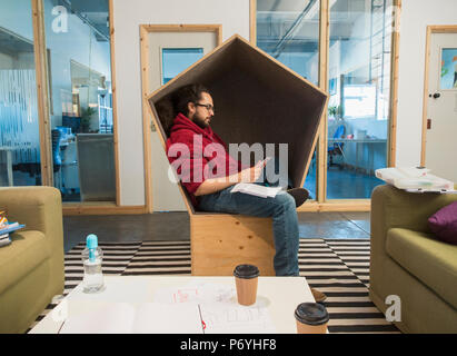 Creative businessman using smart phone in office cubby Stock Photo