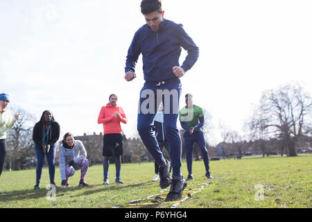 Focused man doing speed ladder drill in sunny park Stock Photo