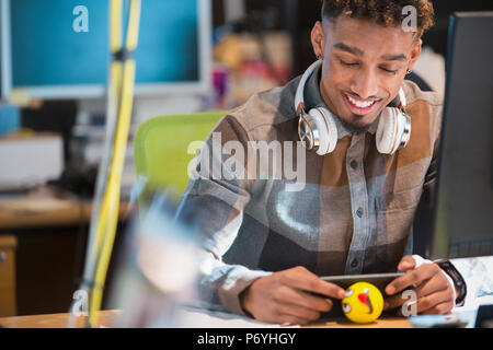 Creative businessman with headphones texting with smart phone at desk Stock Photo