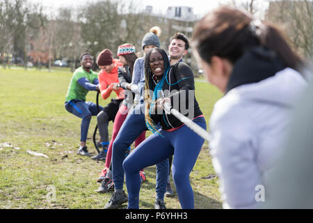 Determined team pulling rope in tug-of-war in park Stock Photo