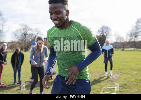 Smiling man doing speed ladder drill in park Stock Photo