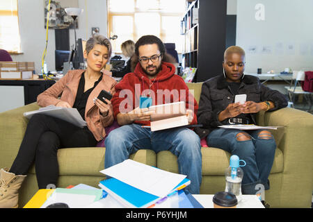 Creative business people using smart phones, meeting in casual office Stock Photo