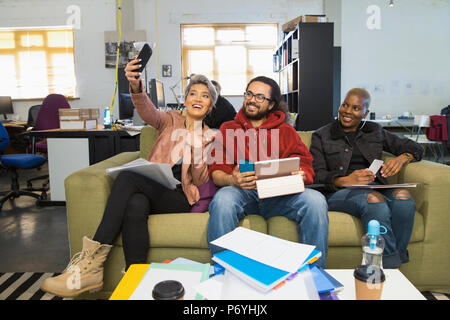 Happy creative business people taking selfie in casual open plan office Stock Photo