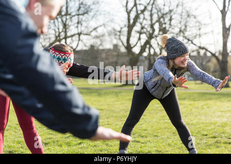 Smiling woman stretching, exercising in park Stock Photo