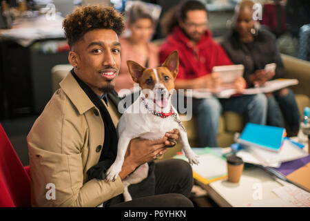 Portrait smiling creative businessman with dog in office Stock Photo