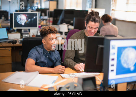 Creative businessmen working at computer in open plan office Stock Photo