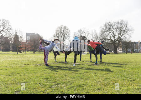 People exercising, stretching in sunny park Stock Photo