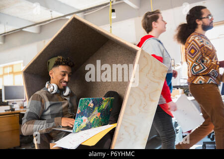Creative businessman working at laptop in cubby Stock Photo