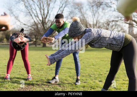 People exercising, stretching in sunny park Stock Photo
