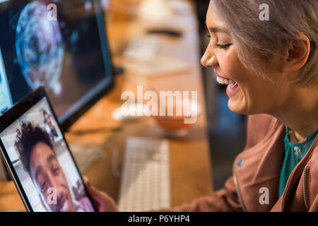 Laughing businesswoman video chatting with businessman on digital tablet Stock Photo