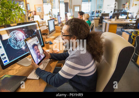 Creative designer video chatting with colleague on digital tablet in office Stock Photo