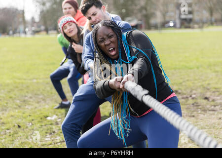 Determined team pulling rope in tug-of-war at park Stock Photo