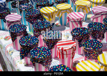 An assortment of colorful containers, on a table, covered with bright colorful paper and secured with elastic bands Stock Photo