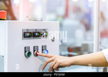 Engineer's hand push red button to shutdown temperature control machine. Temperature control panel cabinet contain digital screen display for temperat Stock Photo