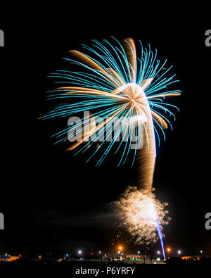 Blue-green and Golden Starburst fireworks with explosions and rocket trails. Stock Photo