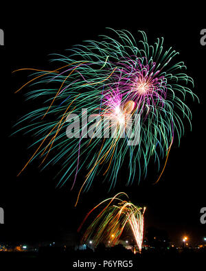 Windswept Multiple Colored Star burst fireworks and rocket trails from the ground. Stock Photo