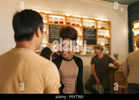 Laughing young woman talking with her friend in a bar Stock Photo