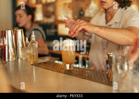 Bartender making cocktails behind the counter of a trendy bar Stock Photo