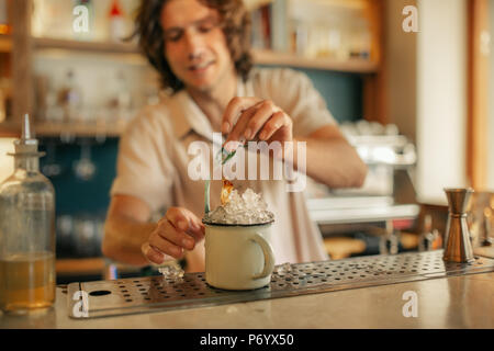 Smiling bartender making drinks behind the counter of a bar Stock Photo