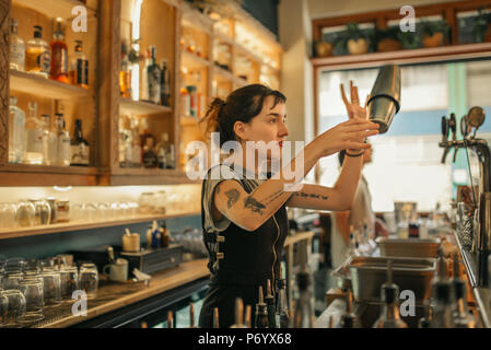 Young female bartender mixing cocktails behind a bar counter Stock Photo