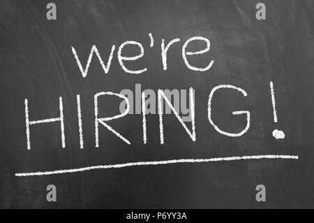 We are hiring announcement chalk text on blackboard or chalkboard as employee professional help wanted concept Stock Photo