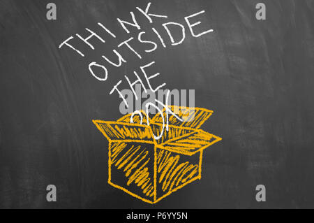 Think outside the box innovation concept with chalk text on blackboard or chalkboard and cardboard sketch drawing Stock Photo