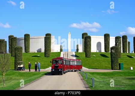 Front view of the Armed Forces Memorial with a red land train in the foreground and people enjoying the setting, National Memorial Arboretum, Alrewas, Stock Photo