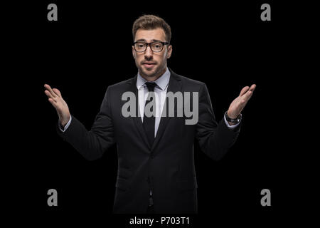handsome doubtful businessman in black suit, isolated on black Stock Photo