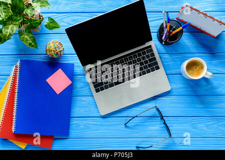Open laptop and stationery on blue wooden table Stock Photo