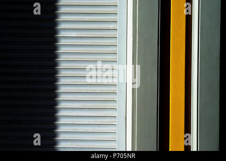 Lines of metal blinds on the wall with wooden boards with a shadow Stock Photo