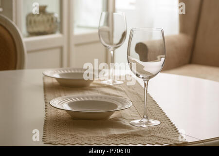 Wineglasses and white plates on table in dining room Stock Photo