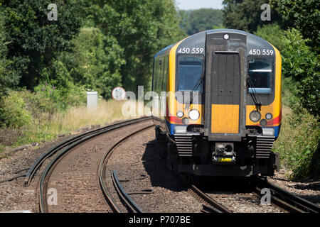 Delayed due to speed limits in hot weather, South Western railway 450 Class commuter train south bound between London Waterloo and Southampton Central Stock Photo