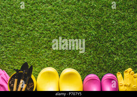 top view of rubber boots, protective gloves and flower pot with gardening tools Stock Photo