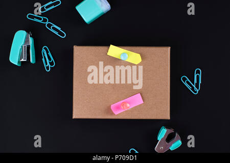 Many multi-colored paper clips and paper on a black background. Office concept. Subjects for the school. Copy space Stock Photo