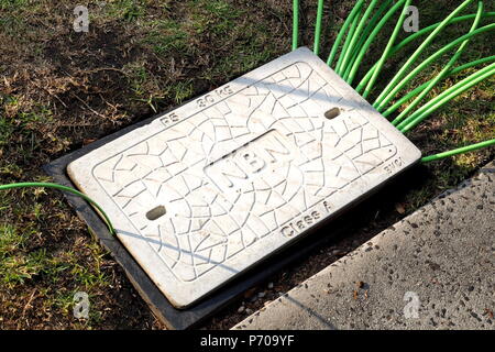 Melbourne, Australia - May 14, 2018: Pit with a concrete man hole cover displaying the NBN word mark with fibre optic cables in and out Stock Photo