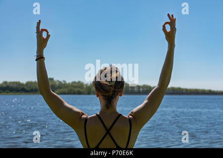 A yoga instructor demonstrates yoga poses during an outdoor yoga session in nature with blue skies and brilliant colours. Stock Photo