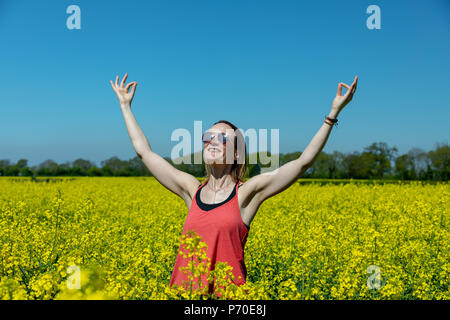 A yoga instructor demonstrates yoga poses during an outdoor yoga session in nature with blue skies and brilliant colours. Stock Photo