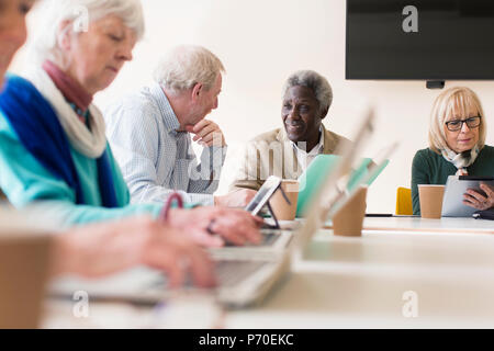 Senior business people talking, using laptops and digital tablets in conference room meeting Stock Photo