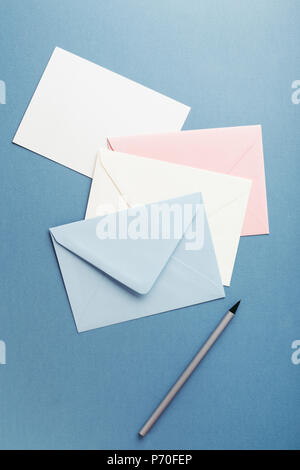 Group of colorful envelopes on blue table with empty card. Correspondence concept. Mockup. Stock Photo