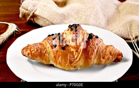 Delicious chocolate croissant with chocolate topping. Gourmet eating scene with wooden table and fresh butter croissant. Stock Photo